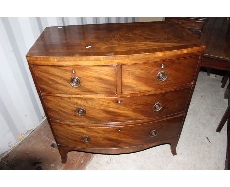 A early 19th Century mahogany chest of drawers, bow fronted, comprising two short over two long drawers, raised on splayed br