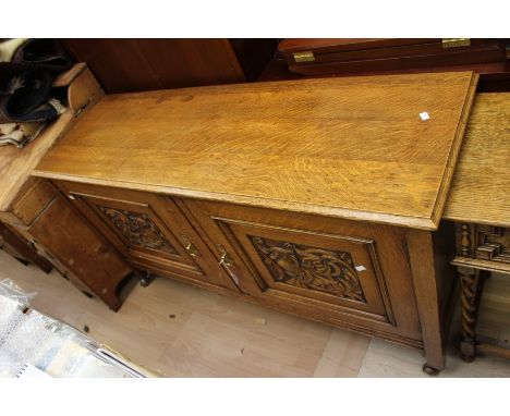 An early 20th Century oak sideboard, fitted with two carved doors, together with an oak side table, fitted with two drawers, 