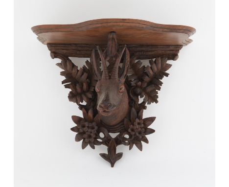 Late 19th/early 20th century carved black forest serpentine shelf carved with a chamois head, and foliage, 35 cms wide x 27 c