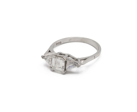 A three stone diamond set platinum ring, the central step cut diamond estimated as weighing approximately 0.7ct, flanked eith