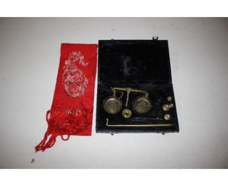 A cased set of small balance scales and weights and a red silk sash