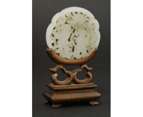 A jade Disc, 20th century, pierced and carved with the He He Erxian within a ruyi border,5.4cm, stand (2)二十世纪 青白玉镂雕和合二仙纹如意牌