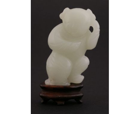 A jade Carving,18th century, of a dancing boy, the figure on one leg, a switch of millet held over his back,5.4cm, wood stand