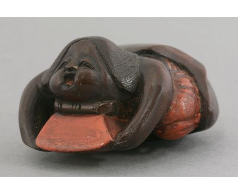 A lacquered wood Netsuke,late 19th century, in the form of a woman crawling from the skin of a chestnut, details in orange/re