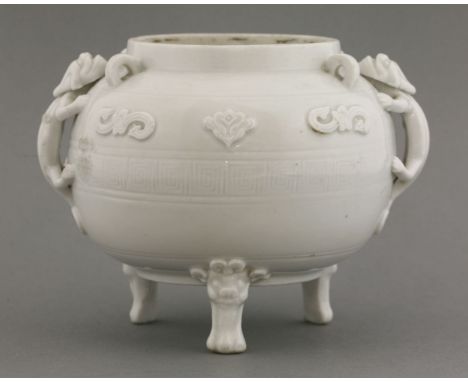 A blanc de Chine tripod Censer,c.1680, the body encircled by key fret beneath sprigged motifs, the sides with chilong handles