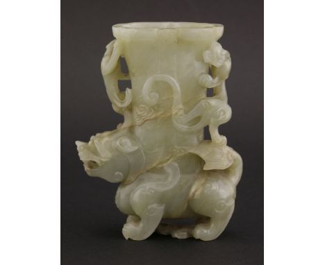 A well carved jade Vase,18th century, in the form of a mythical beast supporting an oval section container, surrounded by chi