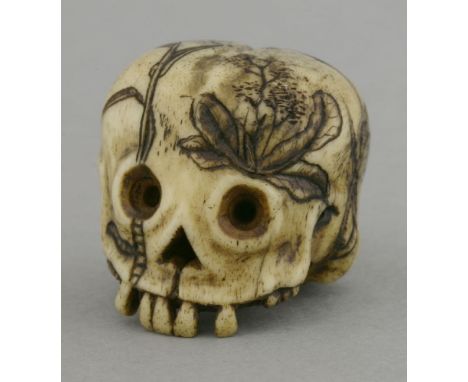 A rare bone Memento Mori Netsuke,probably 18th century, the naively carved skull with missing teeth and black-engraved with v