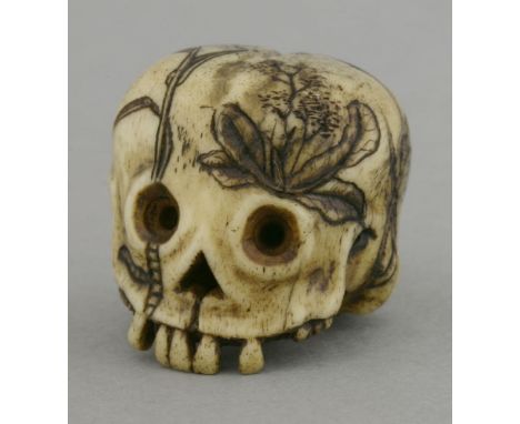 A rare bone Memento Mori Netsuke,probably 18th century, the naively carved skull with missing teeth and black-engraved with v