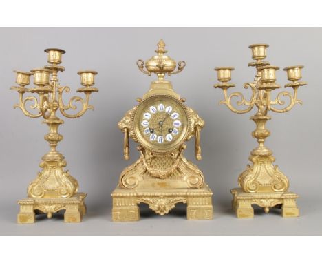 An antique Dutch Louis XIV style mantel garniture, comprising a gilded bronze clock with enamel Roman numerals and two candel