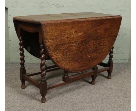 An oak gate leg drop leaf dining table with barley twist supports.