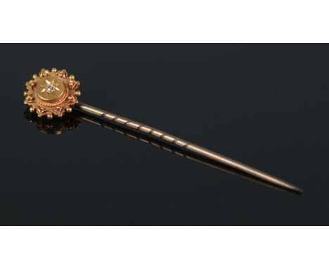 A 15ct Gold stick pin, set with a single diamond within a starburst mount. Length: 5.8cm