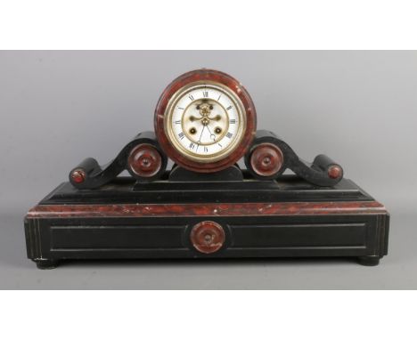An antique black slate and marble drumhead mantel clock, with a visible escapement and Roman numerals, movement marked "H. Lu