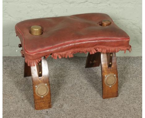 A vintage camel saddle stool with Egyptian style legs, W46 x D29 x H34cm.