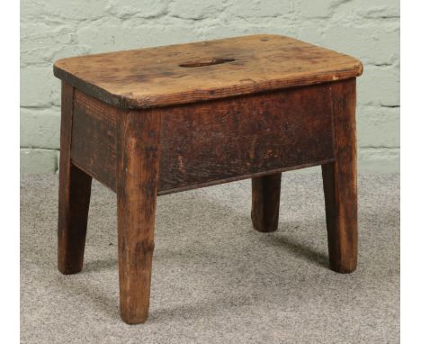 An antique rustic pine stool. Height 35cm, Width 43cm, Depth 27cm.