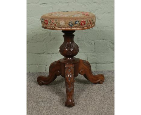 A Victorian carved rosewood adjustable piano stool with bulbous column and tripod base. With tapestry covered seat.