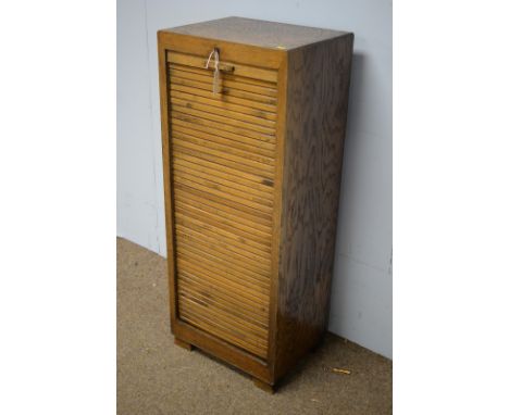 A 1930's oak folio cabinet, the rectangular top with tambour front door enclosing interior folio slides, raised on plinth bas