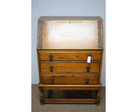 A 1940's oak bureau, the rectangular top above a fall-front door, enclosing an arrangement of drawers and pigeon holes, above