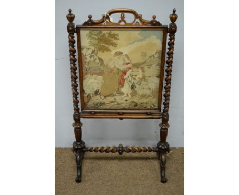 A Victorian rosewood firescreen, with central needlework panel, contained within a rosewood frame and flanked by barley twist