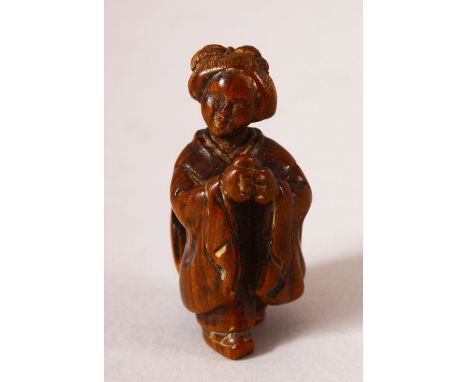 A JAPANESE MEIJI PERIOD CARVED WOOD NETSUKE OF A LADY - The lady stood with her hands together, signed to her back " Tadatomo