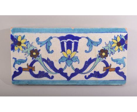 AN INDIAN MULTAN GLAZED TERRACOTTA TILE PANEL, with foliate motif, 30.5cm long.