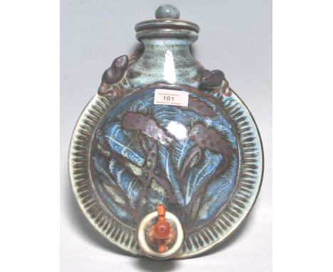 A vintage retro 20th century studio art pottery flask /keg of round moonflask form having a wooden tap to the base, being gla