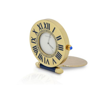 A Cartier brass and blue enamel quartz travel clock. The clock having a fold over stand face with roman numeral dial, with bl