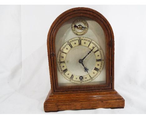 An oak cased dome topped mantel clock by W&H, silvered dial with applied chapter ring and Roman numerals, timepecce oly movem