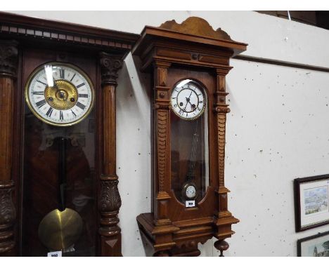 A Vienna style wall clock in a walnut case with carved and turned decoration, glazed opening door displays the white enamel d