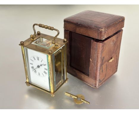 A Edwardian French brass four glass travelling clock with folding handle to top white enamel dial with roman numerals and bev