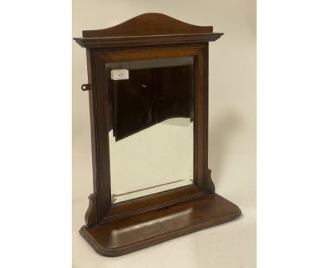 An Edwardian walnut framed wall hanging mirror, the arched top over reeded frame enclosing bevelled plate and above an open s