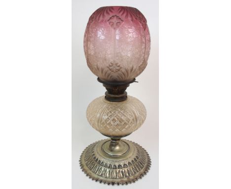 A VICTORIAN OIL LAMP the graduated clear to cranberry shade with etched decoration above a cut glass reservoir and upon and E