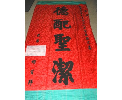 A CHINESE SILK BANNER IN RED AND BLACK WITH CALLIGRAPHY 81cm x 191cm and a larger banner with black lettering on a silk patte