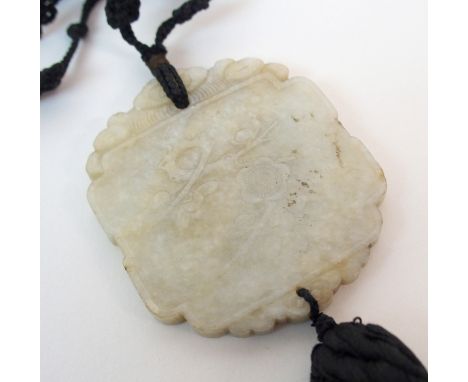 A CHINESE JADE PENDANT carved to one side with blossom, the other characters with cord and nut necklace, the plaque 6cm x 5cm