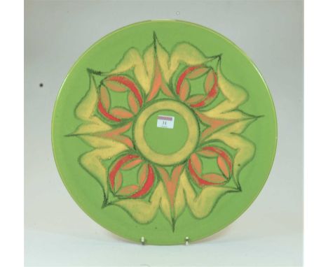 A large Poole Pottery Delphis charger on a green ground with red, orange and yellow floral decoration, having printed Poole E