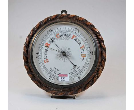 An early 20th century aneroid barometer housed within a carved oak ropetwist surround, dia. 27cm