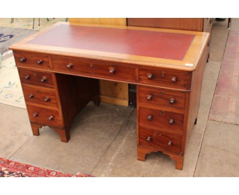 A VICTORIAN MAHOGANY PEDESTAL DESK with a red leatherette inset top, nine drawers with turned knob handles, and all raised on