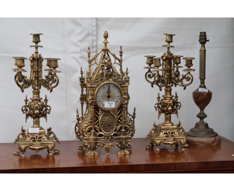 A GILT METAL GARNITURE CLOCK of pierced scrolling architectural form, 46cm high with two five branch candelabra and a gilt ha