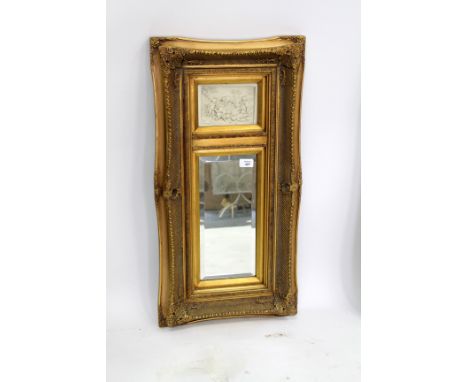 A GILT FRAMED WALL MIRROR with an inset plaque depicting cherubs playing, 40cm x 80cm