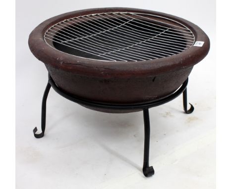 A CERAMIC BARBECUE  of semi-spherical form with stainless steel grill and black painted iron stand, 49cm diameter