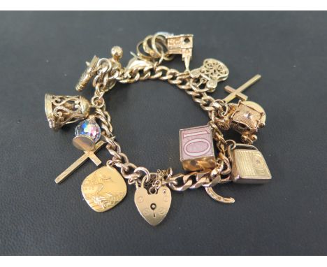 A 9ct gold curb-link bracelet - Suspending sixteen assorted charms to the padlock clasp - Hallmarked London - Length 17cms - 