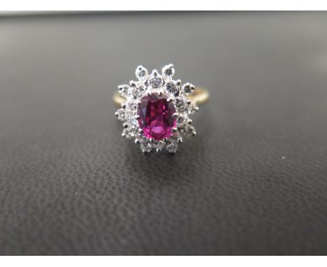 An 18ct gold ruby and diamond cluster ring - The oval ruby within a brilliant-cut diamond double surround - Hallmarked London