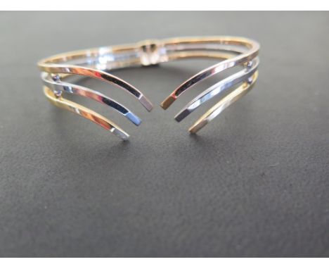 A tri-colour hinged cuff bangle - Of chevron design - Stamped 750 (18ct) - Inner diameter 6.5cms - Weight approx 13.6gms
Cond