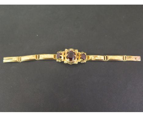 A French 18ct gold garnet panel bracelet - The central panel set with three graduated octagonal-shape garnets - To the rectan