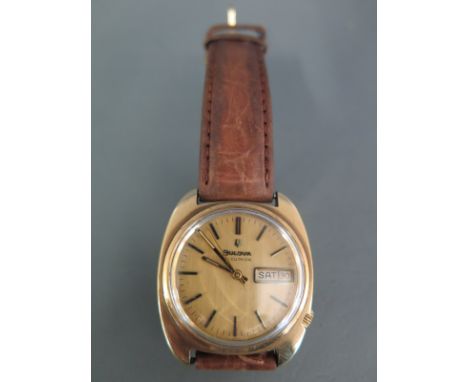 A gentleman's Bulova Accutron wristwatch in 9ct gold case, champagne dial with baton numerals and a day-date adjustment - run