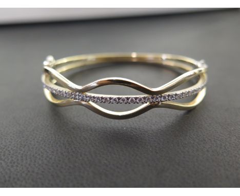 A 9ct gold cubic zirconia bangle - Of openwork design, the cubic zirconia line to the scalloped sides - Hallmarked London - I