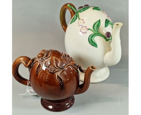 Two unusual novelty ceramic teapots, one brown glazed, the other on a white ground, both with raised floral and foliate decor