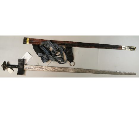 A Sudanese Kaskara sword, with fluted steel blade and leather covered grip with brass pommel, in leather scabbard with yellow