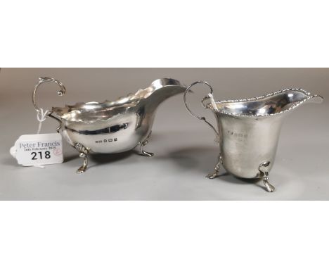 Silver Georgian style sauce boat on three paw feet, together with a silver helmet shaped cream jug, Birmingham hallmarks. 4.7