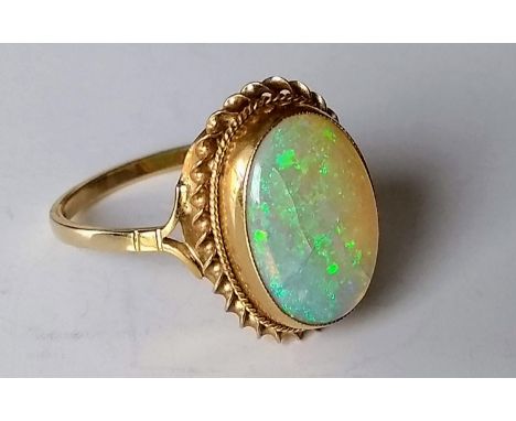 An cabochon opal ring with rope-twist border on a 9ct gold setting, size Q, hallmarked, 3.11g 