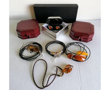 An assortment of contemporary cased Baltic amber jewellery to include four pendants with silver and leather mounts and a pair